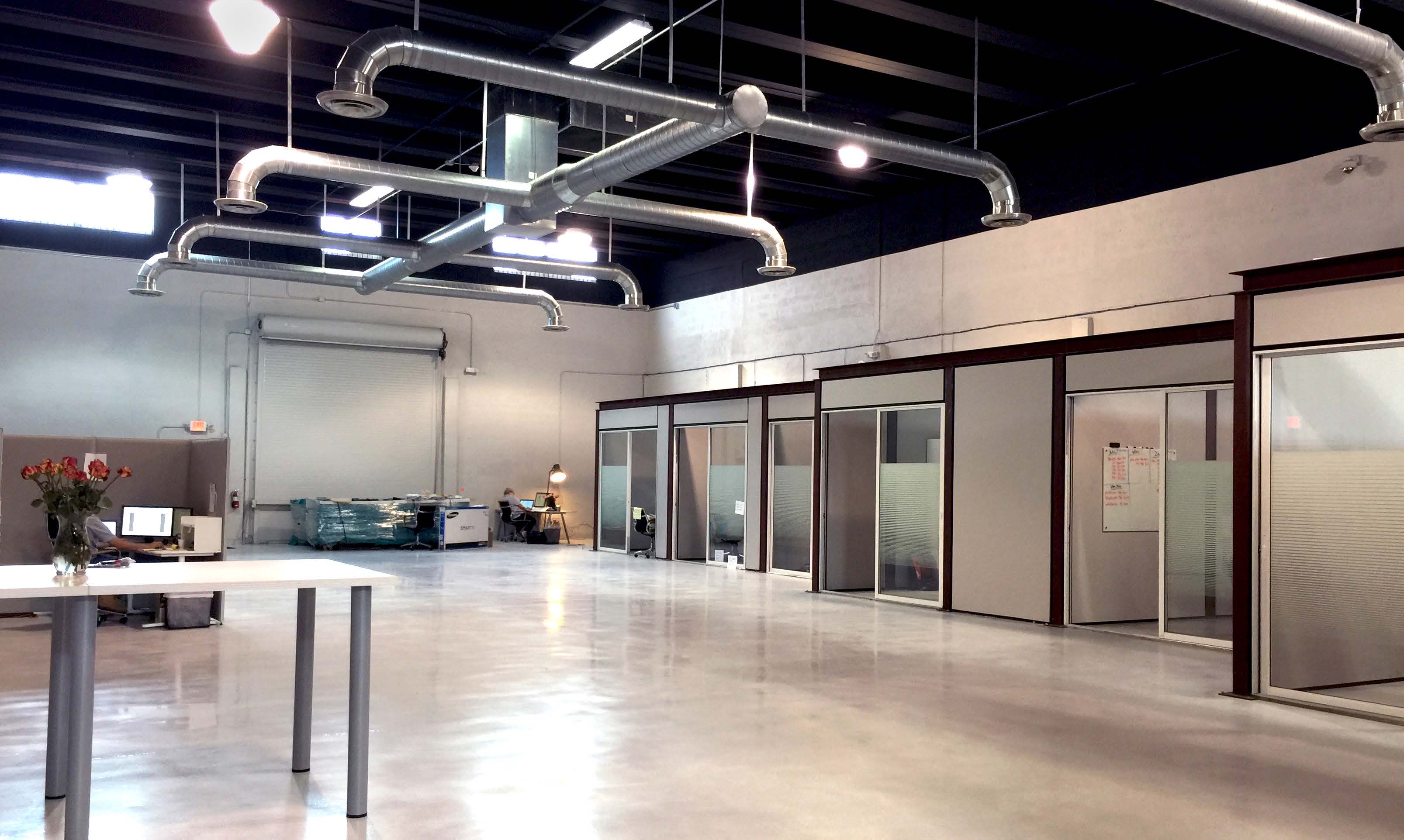 Inside the building: an open double-height floor, polished concrete and glass-walled offices at the back